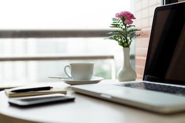 Selected focus cup of coffee and laptop on with pink flower