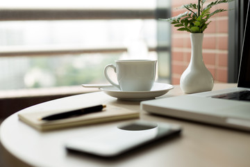 Selected focus cup of coffee and laptop with pen