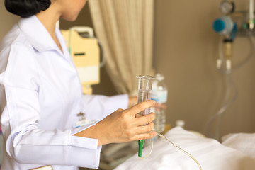 Nurse giving patient water using glass syringe to irrigate nasogastric tube in hospital