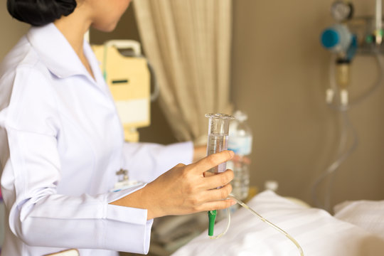 Nurse Giving Patient Water Using Glass Syringe To Irrigate Nasogastric Tube In Hospital