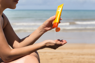 Woman hands putting sunscreen from a suncream bottle
