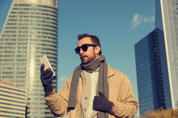 Modern guy using cellphone in the European city.