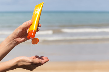 Woman hands putting sunscreen from a suncream bottle