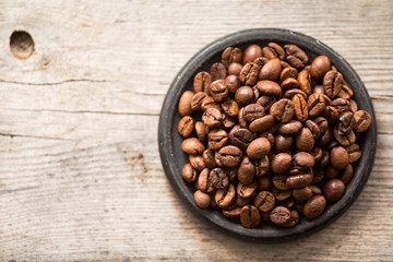 Roasted coffee beans on black plate on wooden background
