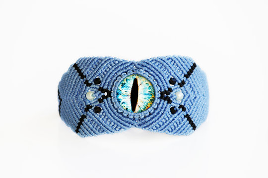 blue bracelet for the hand from waxed thread, and blue dragon eye in the technique of macrame on a white background.