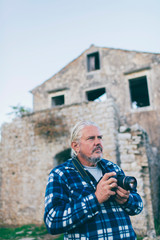 Tourist with gray hair and beard photographing architecture of Old Perithia, Corfu, Greece.