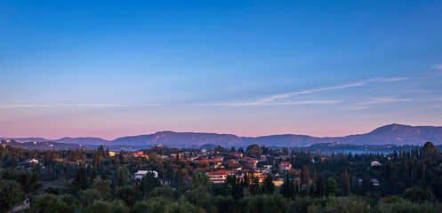 Houses in misty hills lit by morning sun. Corfu, Greece.