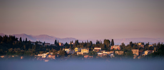 Skyline of mountains and hills with houses at sunset. Corfu island, Greece.
