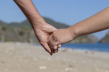 Couple hands held together on a natural sea background
