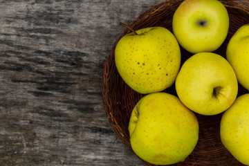 Ripe green apples in a basket on rustic wooden table