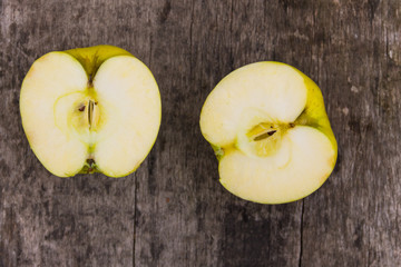 Halves of green apple on rustic wooden table