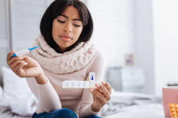 Thoughtful ill woman looking at the pill box