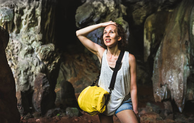 Obraz premium Young woman traveler at cave entrance on island hopping in Cheow Lan Lake - Wanderlust trip and travel concept with adventure girl tourist wanderer on excursion in Thailand - Warm contrast filter