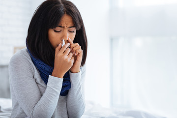 Sad woman using nasal drops at home