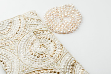 Obraz premium Female white bag and pearl necklace on a white background top view