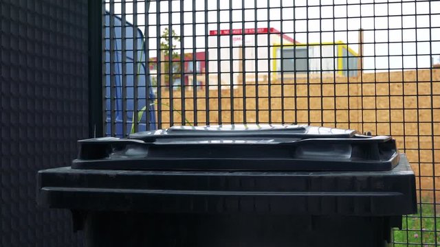 A man throws a full trash bag into a bin - closeup