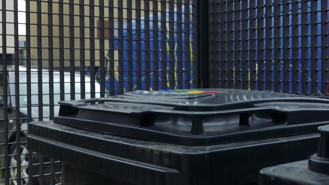 A man throws a full trash bag into a bin - closeup