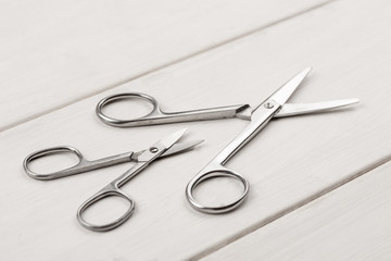 Big and small metal scissors on a white wooden table