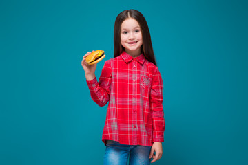 Cute little girl in checkered shirt with brunet hair hold burger