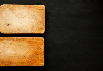 Two empty wooden cutting boards on a dark background, top view