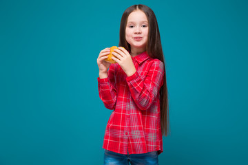 Cute little girl in checkered shirt with brunet hair hold burger