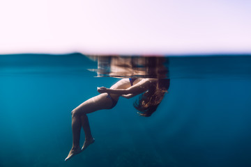 Woman floating in ocean, girl is relaxing. Underwater photo