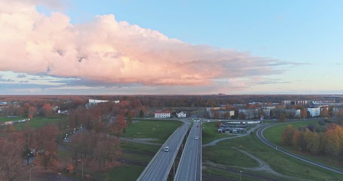 Aerial footage of traffic, cars and buses on the bridge, Jõhvi, Estonia. Beautiful sunset with amazing pink clouds over the city.