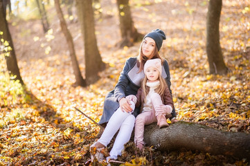Mom and daughter on the background of the sunset in the autumn forest. Family idyll.