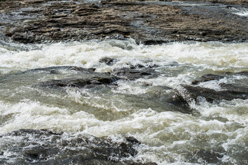 Fast stream of a mountain river runs through the stones.