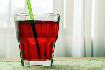 A glass with pomegranate juice on a wooden table.