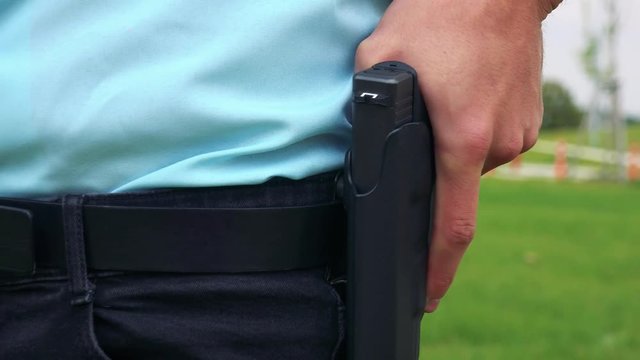 A police officer rests his hand on the gun in the holster - closeup