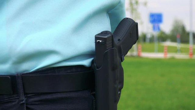 A police officer replaces a gun into the holster - closeup