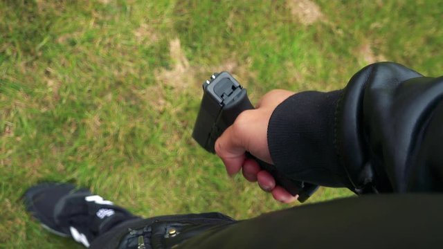 A man holds a gun - closeup from above on the hand