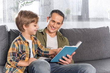 father and son reading book together