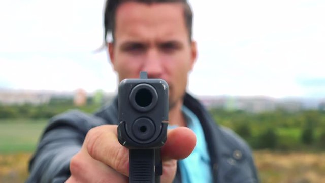 A criminal points a gun at the camera - closeup