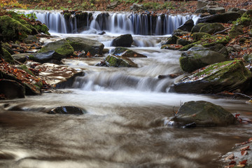 Fototapeta na wymiar Beautiful streams and small waterfalls near the big Carpathian waterfall Shypit. In the autumn.