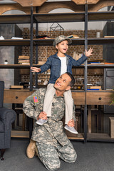 Obraz na płótnie Canvas son riding on military father shoulders