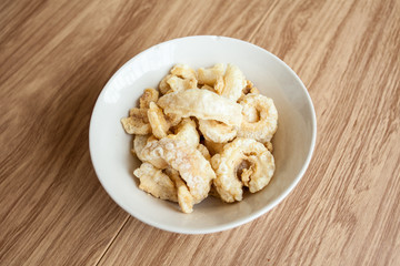 Fried pork rince or Crispy pork skin in white bowl on the wood table, North Thailand food cook from prok skin to fried