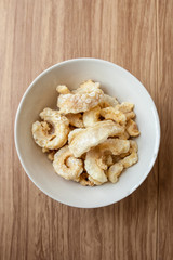 Fried pork rince or Crispy pork skin in white bowl on the wood table, North Thailand food cook from prok skin to fried