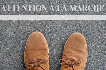 Chaussures devant une ligne avec écrit attention à la marche 