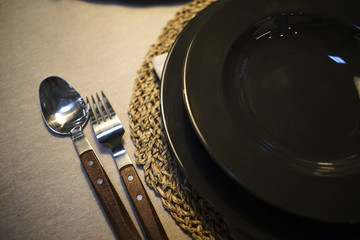 Black dishes. On a wooden table. Wooden spoon and fork