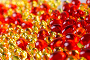yellow and red medical capsules on a mirror surface