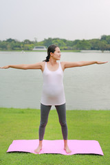 Pregnant woman doing yoga in the public park.