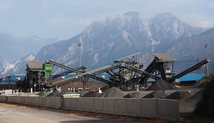 Conveyor belts with several piles of gravel in a plant under the Alps