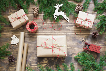 Christmas giftbox and presents wrapping in craft paper and decor on wooden board. Flat lay. Top view.