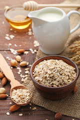 Oat flakes in bowl and spoon on wooden table