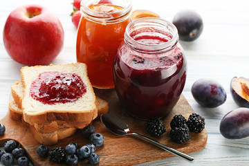 Bread with plum jam and berries on wooden table