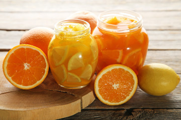 Lemon and orange jam in glass jars on wooden table