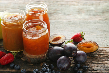 Glass jars with different kinds of jam on wooden table