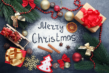 Inscription Merry Christmas on wheat flour background with fir-tree branches, gift boxes and baubles